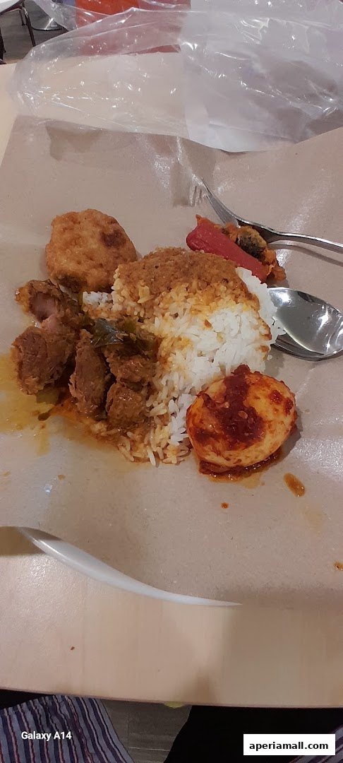 A plate of rice with meat, fried chicken, and a hard-boiled egg with chili sauce.