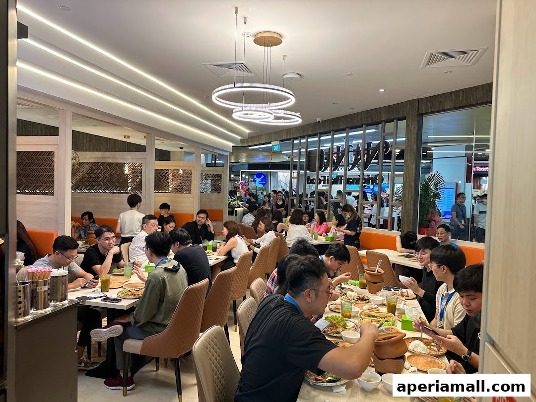 A busy Thai restaurant interior with many diners enjoying their meals at tables.