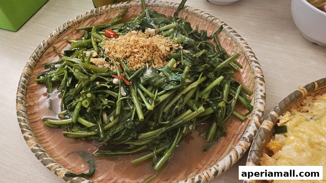 A close-up shot of stir-fried water spinach with garlic and chili on a woven plate.