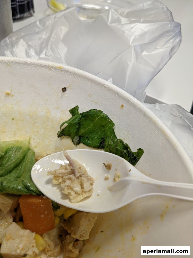 A close-up of a partially eaten salad with a spoon holding a bite of food.