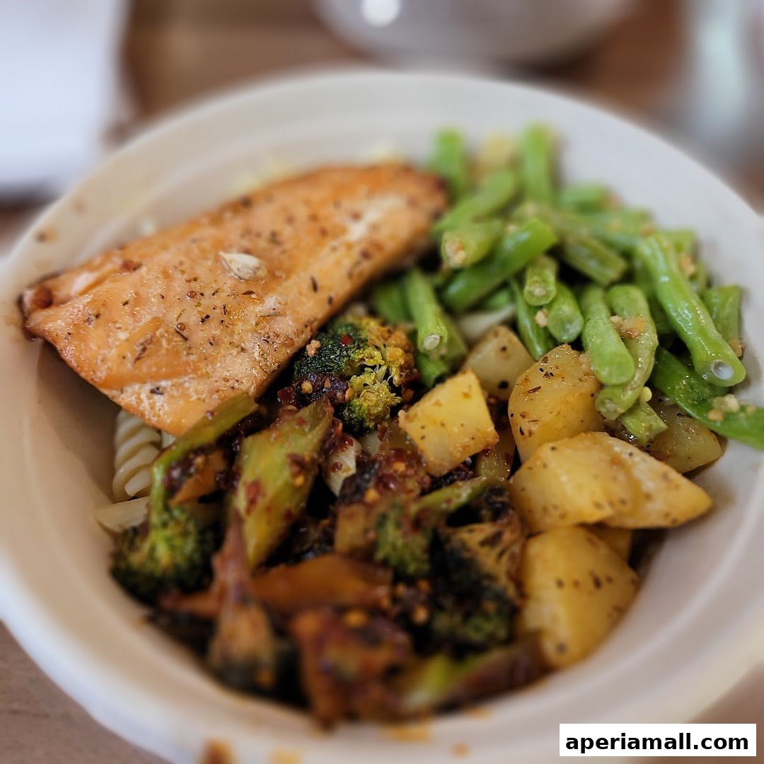 A close-up of a healthy salad bowl with salmon, broccoli, potatoes, and green beans.