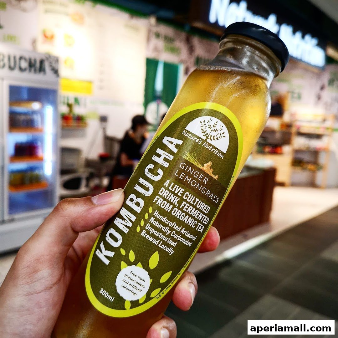 A hand holds a bottle of Ginger Lemongrass Kombucha from Nature's Nutrition.