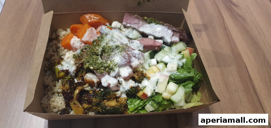 A healthy salad bowl with steak, quinoa, roasted broccoli, carrots, and fresh greens.