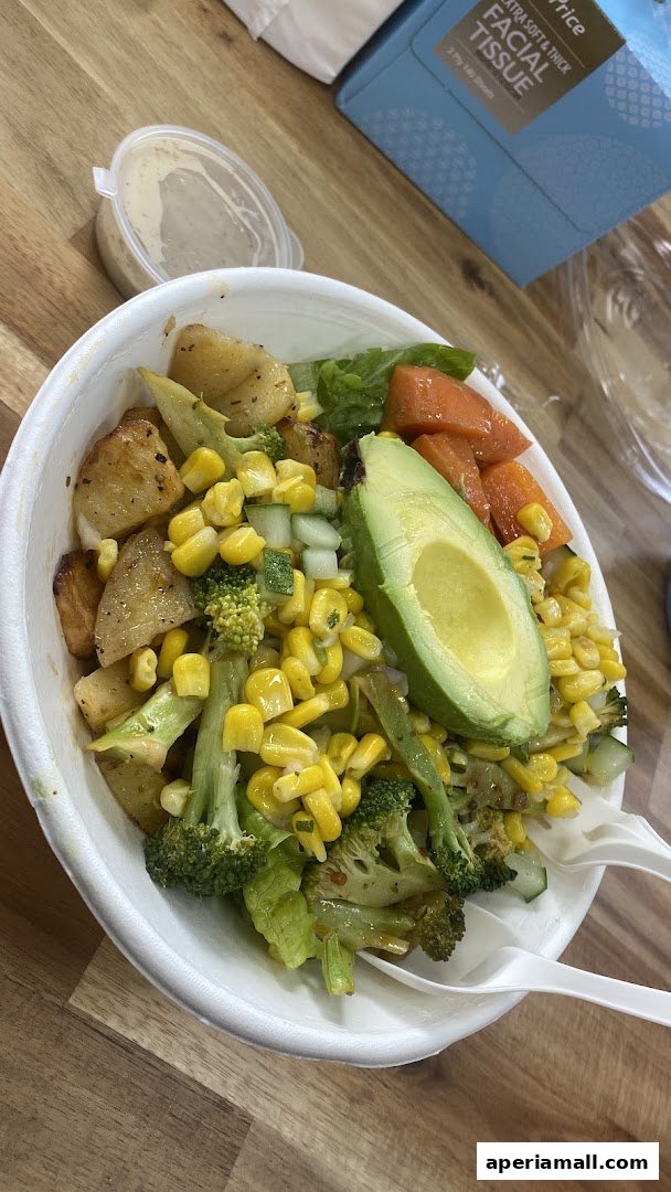 A close-up of a healthy salad bowl with avocado, corn, broccoli, and potatoes.