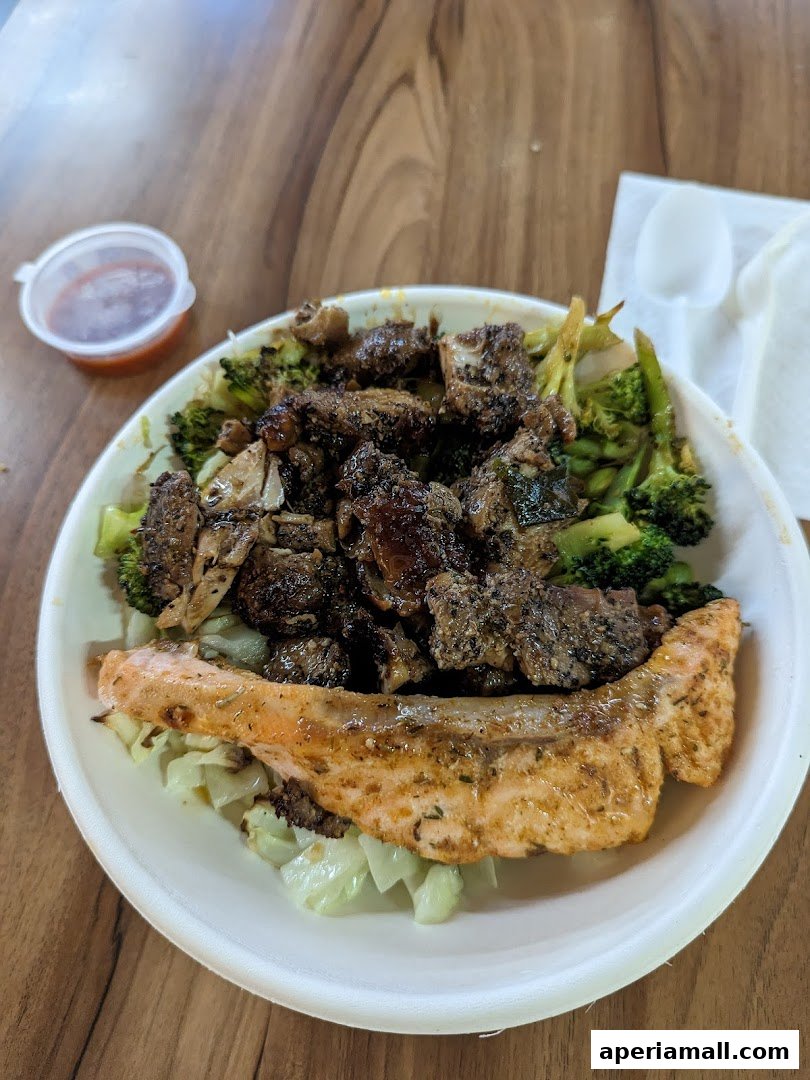 A healthy salad bowl with salmon, grilled meat, and broccoli, served with a side of sauce.