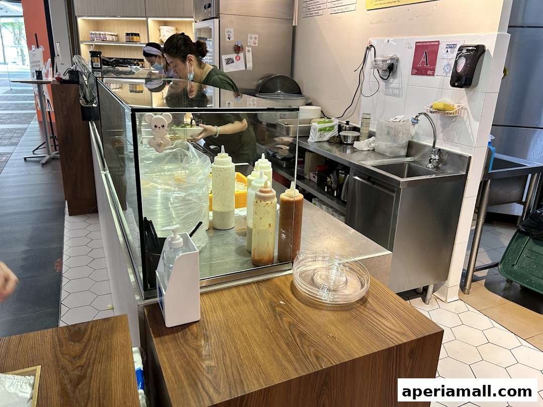 Staff preparing food behind a counter with sauces and ingredients at a healthy eatery.