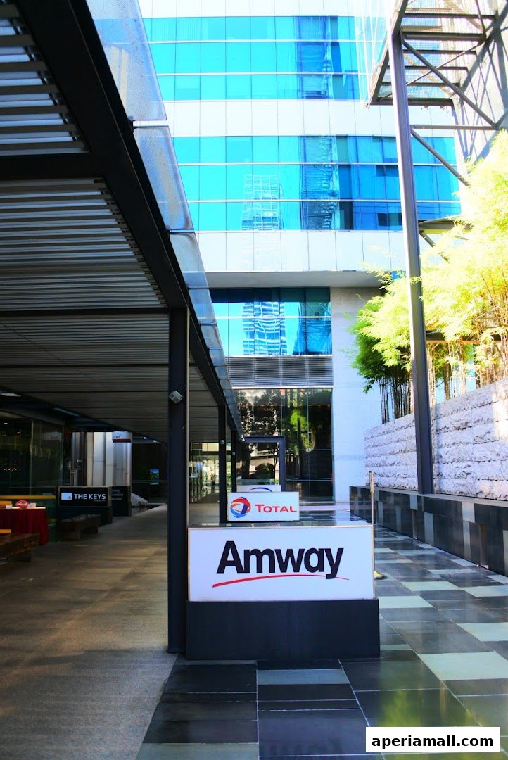 An Amway store sign is displayed outside a modern building with blue glass windows.