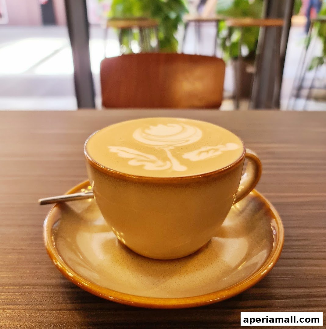A close-up of a latte with intricate latte art in a tan mug on a saucer.