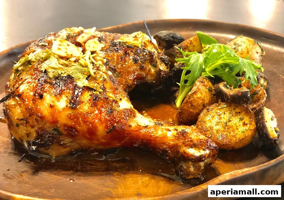 A close-up shot of a delicious roasted chicken leg quarter with crispy potatoes and greens.
