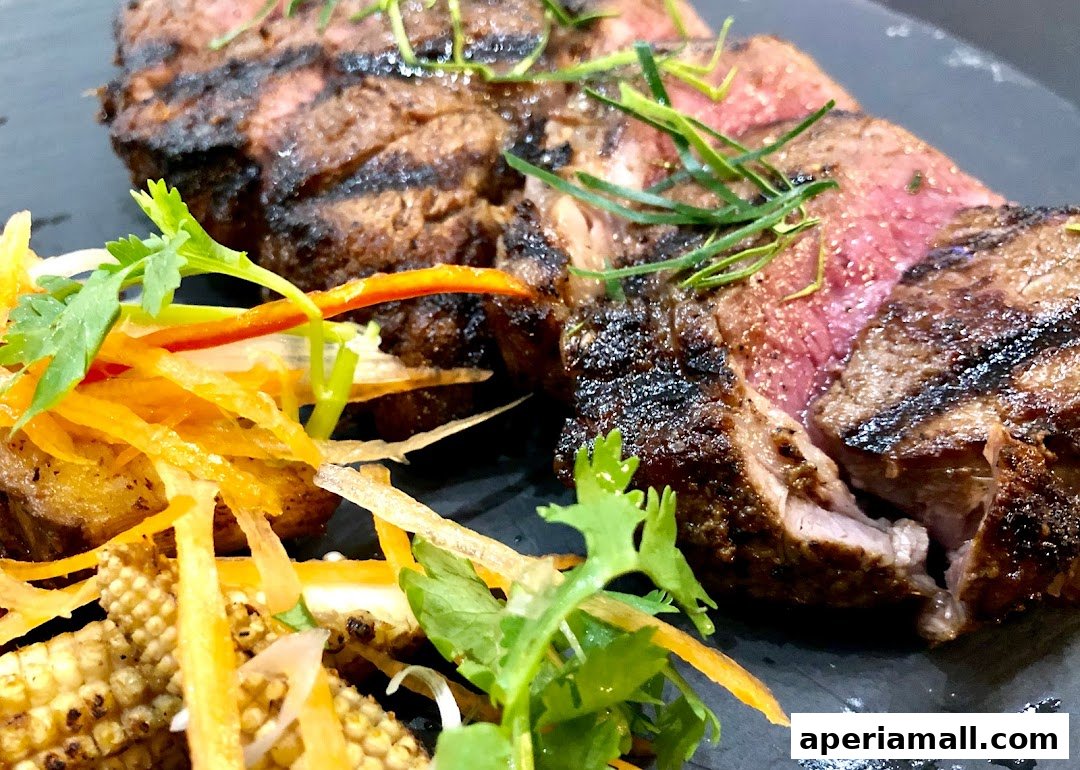 A close-up of perfectly grilled steak, garnished with fresh herbs and a side salad.