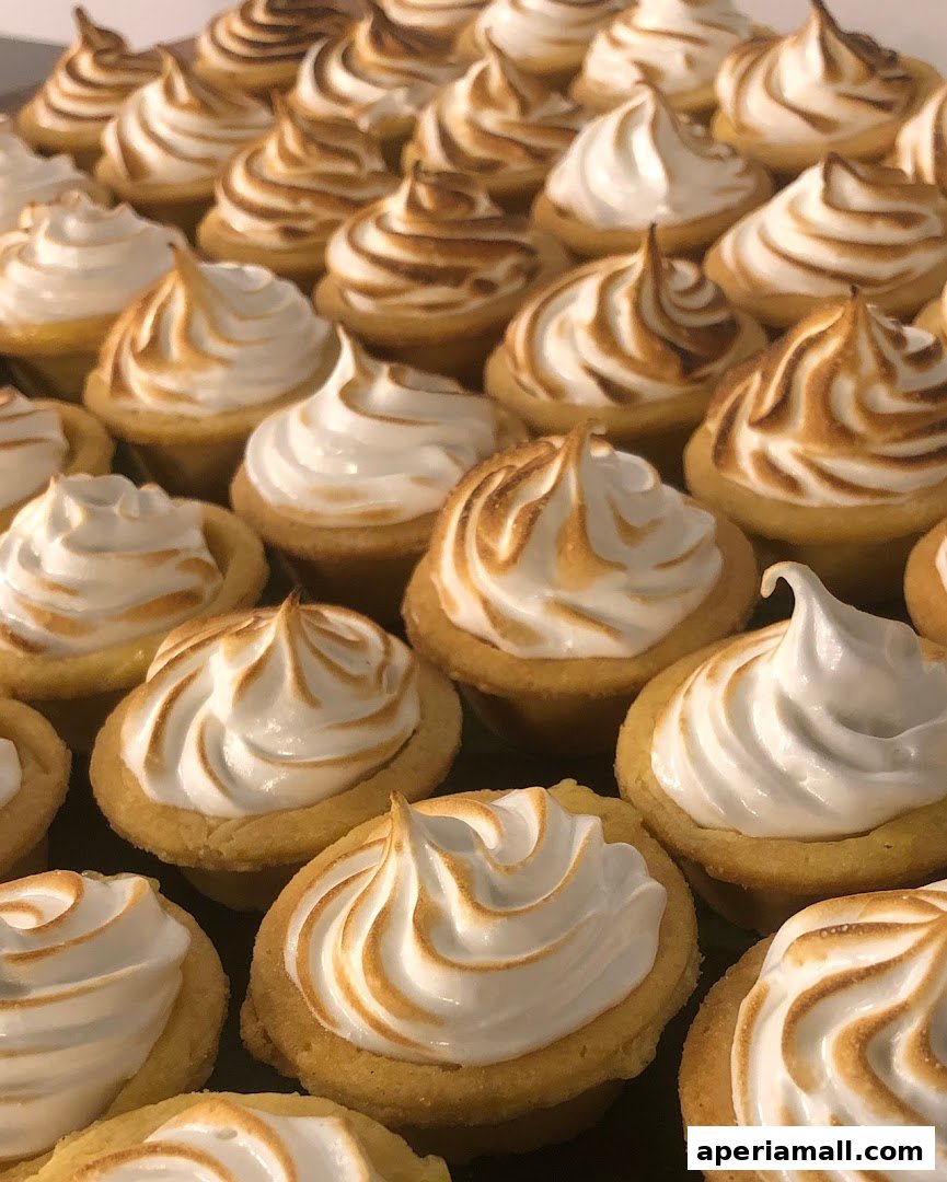 A close-up shot of numerous mini lemon meringue tarts with perfectly torched meringue.