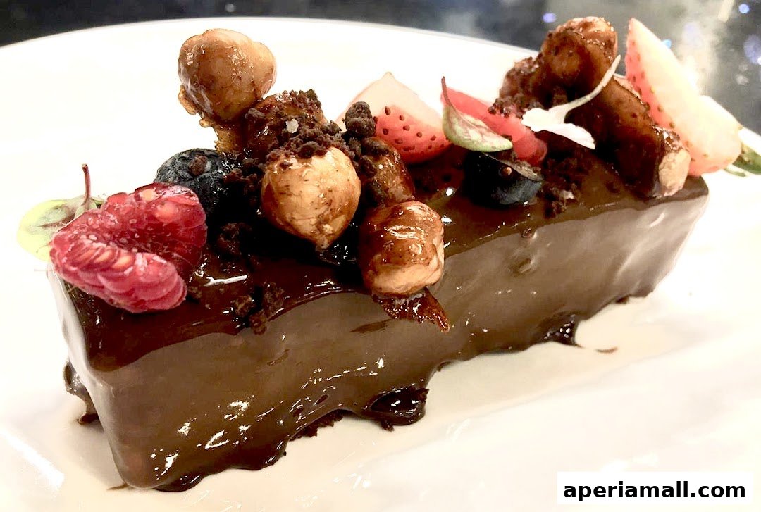 A decadent chocolate dessert topped with fresh berries and nuts on a white plate.
