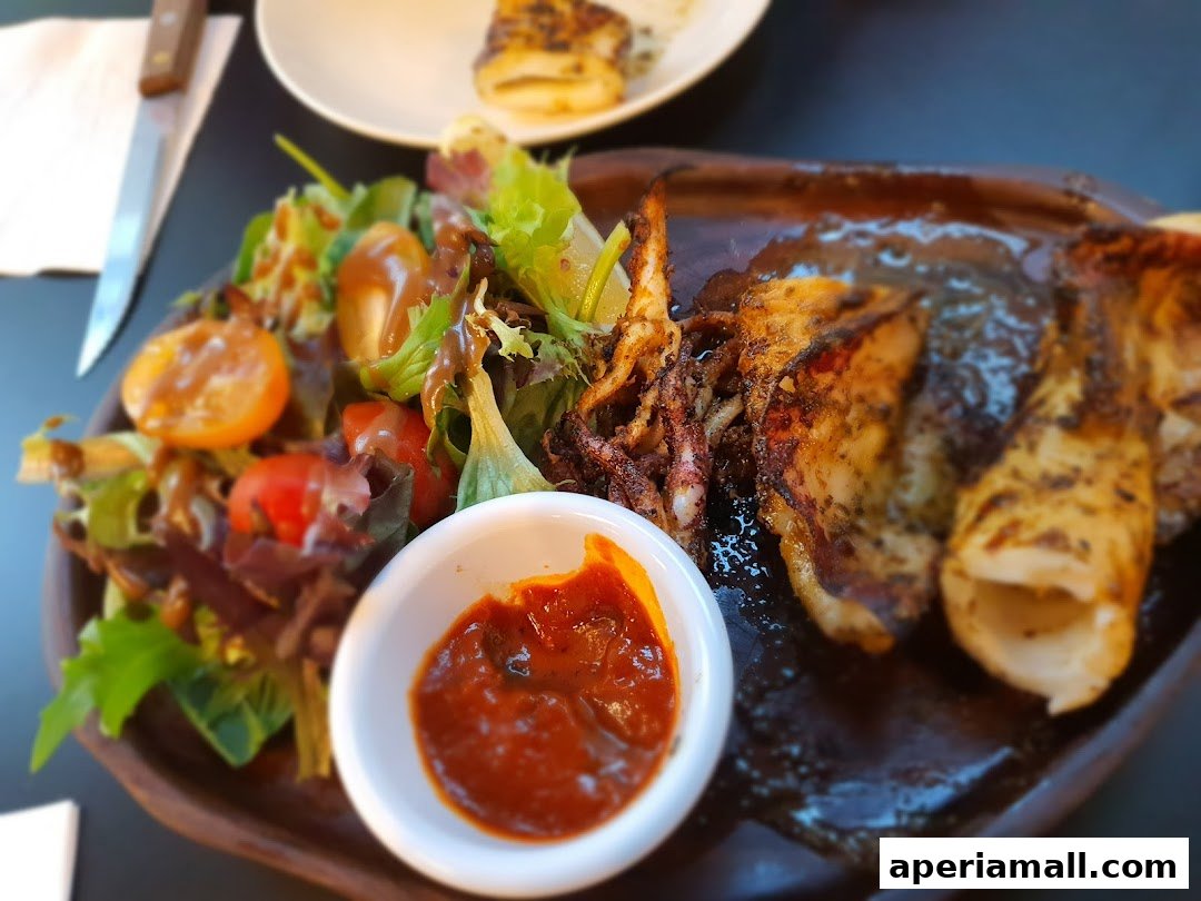 A close-up of grilled calamari served with a fresh salad and dipping sauce.