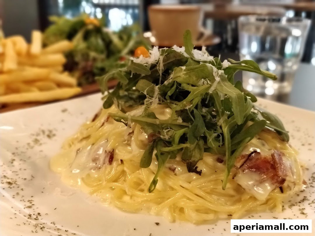 A close-up of a creamy pasta dish topped with fresh greens and parmesan cheese.