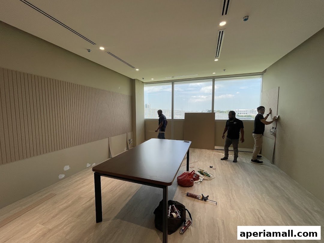 Workers installing decorative panels on the wall of a room with a large table.