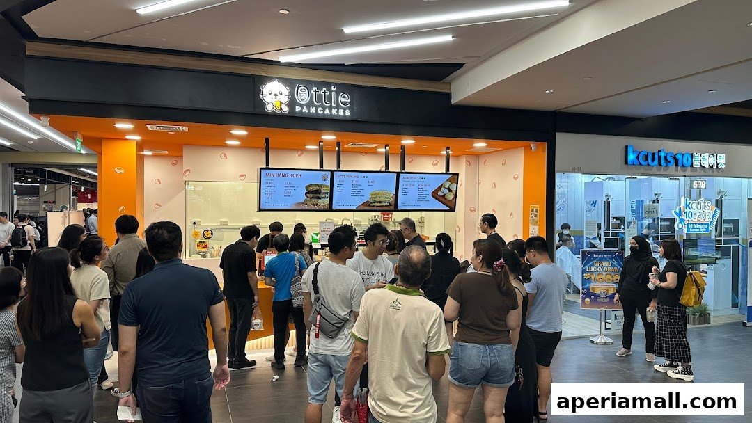 A queue of people waiting outside Ottie Pancakes, a food stall with digital menus displaying pancake options.