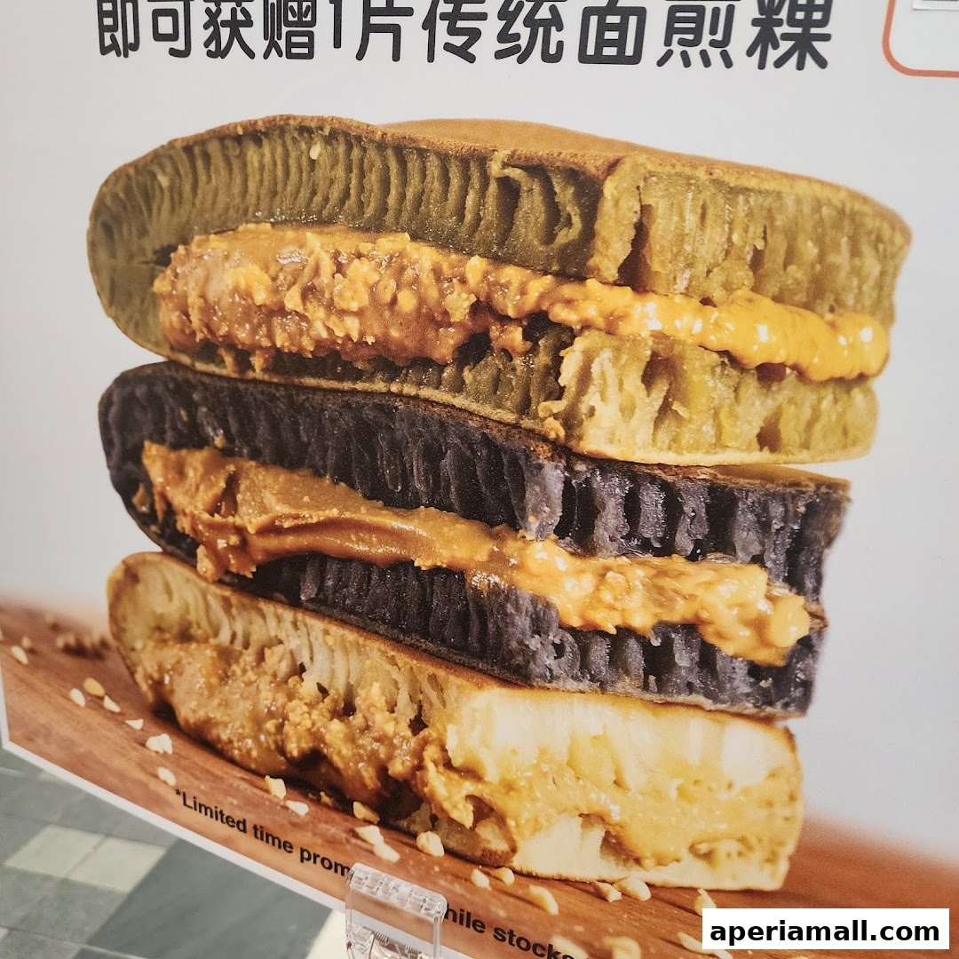 A stack of three colorful pancakes filled with peanut butter, presented on a wooden board.