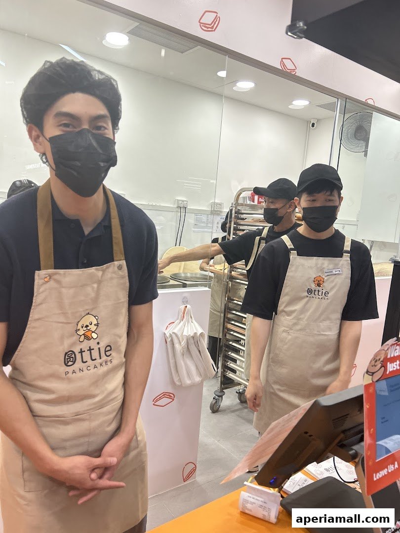 Staff members in aprons at Ottie Pancakes, with a glimpse of the kitchen and counter.
