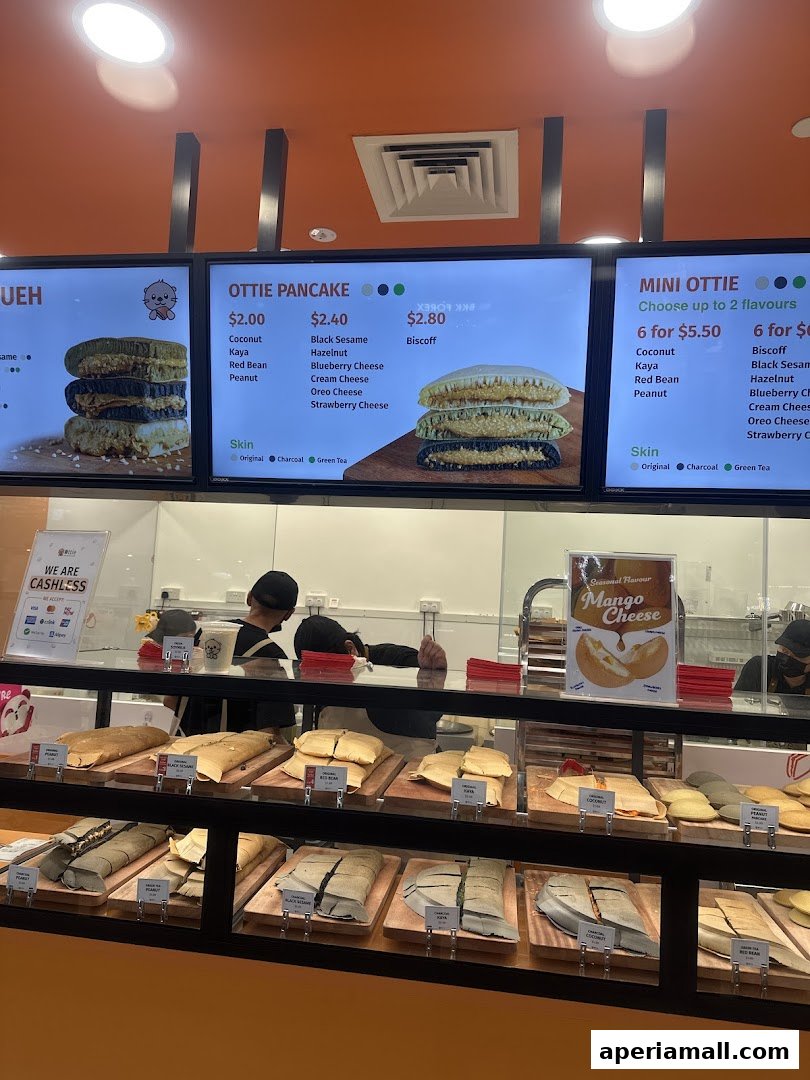 A display of Ottie Pancakes with various flavors and prices shown on screens and in a display case.