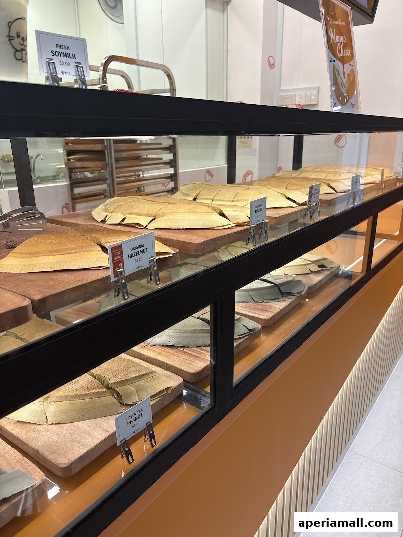 Display case filled with various flavors of pancakes and a sign for fresh soymilk.