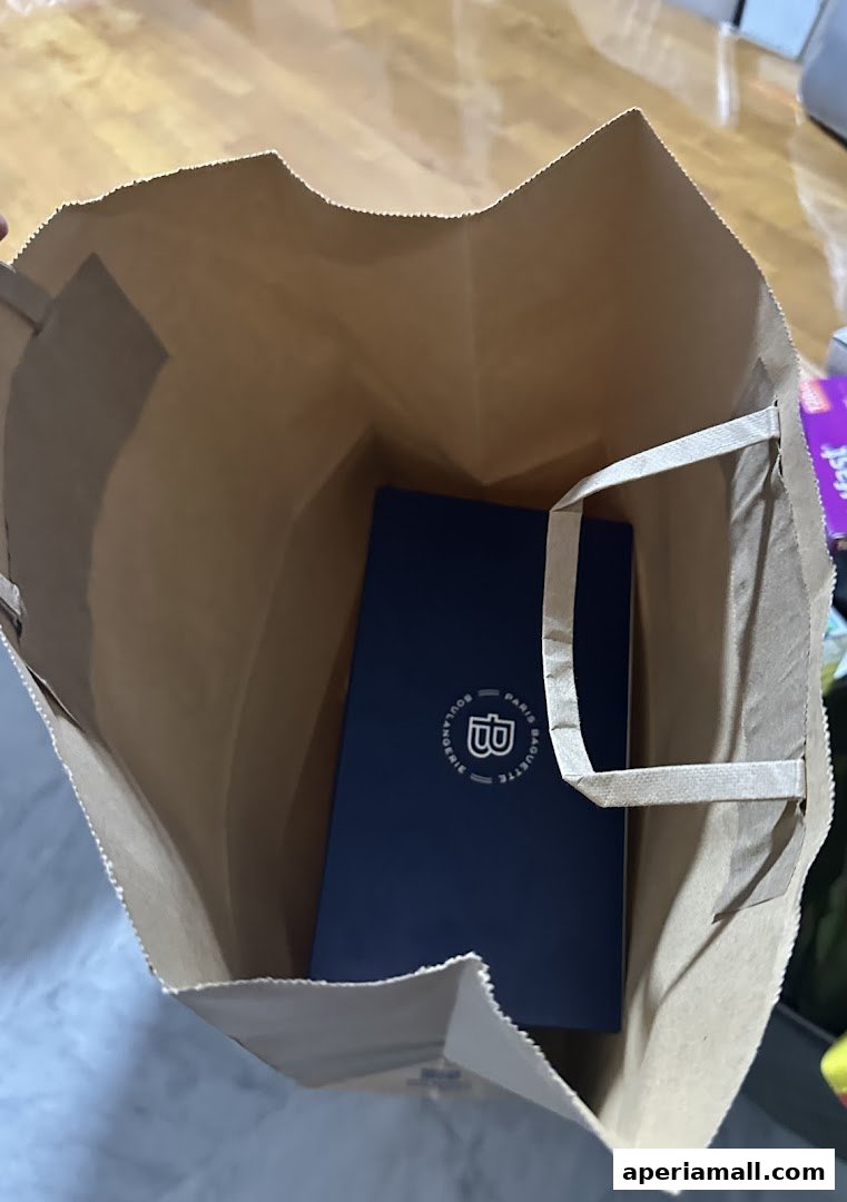 A brown paper bag with a blue box from Paris Baguette inside.