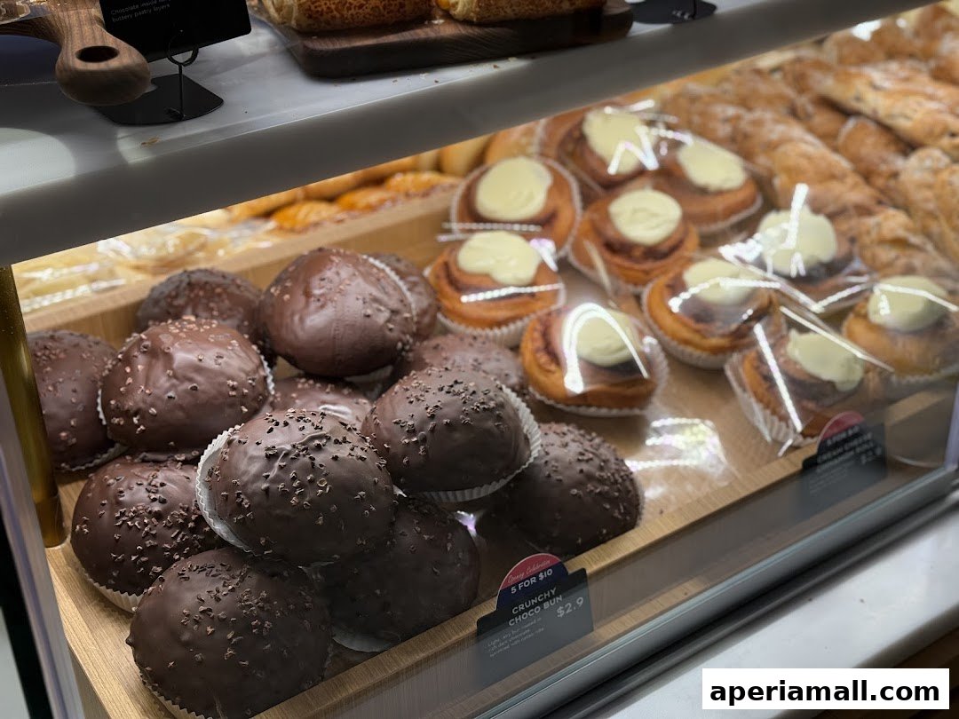 A display case filled with various baked goods, including chocolate buns and cream-filled pastries.