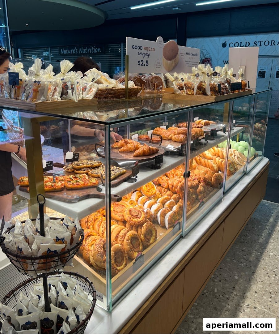 A display case filled with various pastries, breads, and baked goods at Paris Baguette.