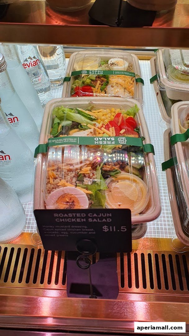 Pre-packaged salads and Evian water bottles displayed in a refrigerated case.