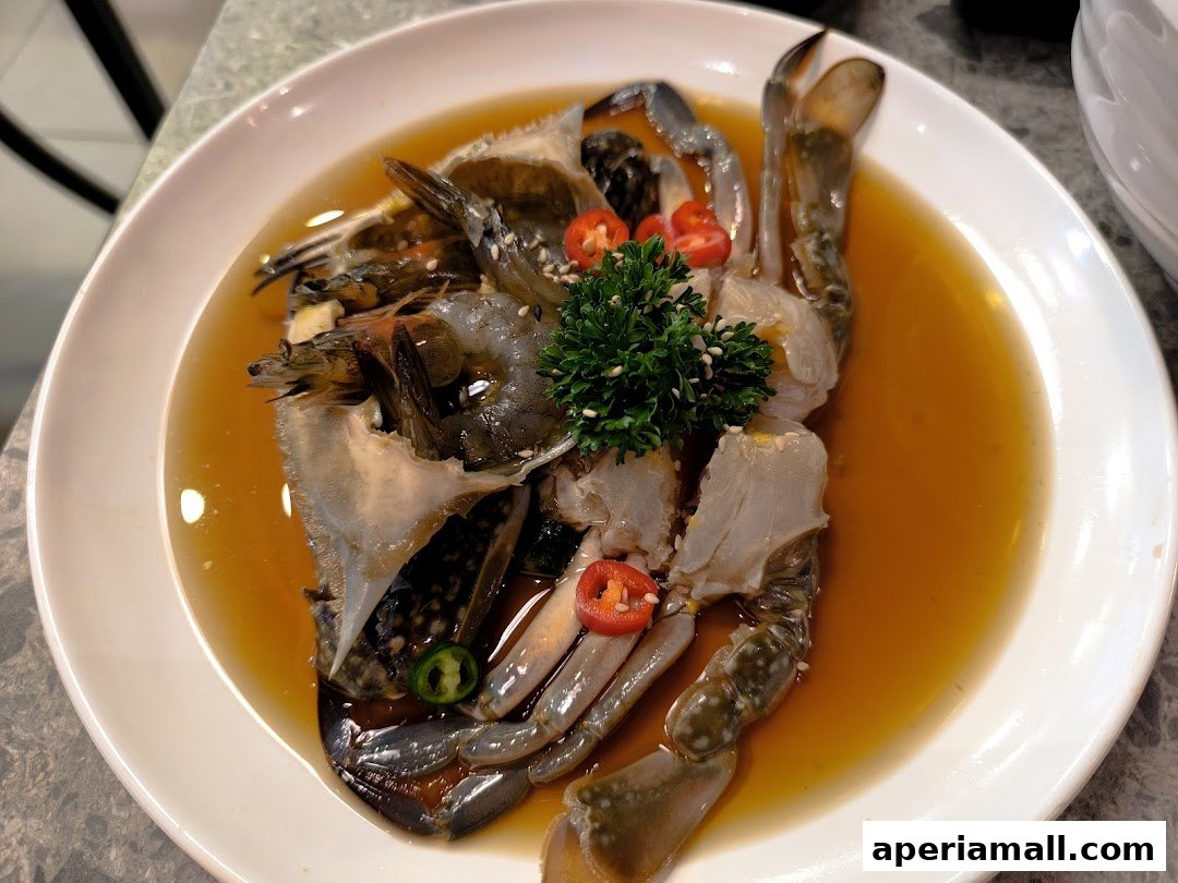 A plate of marinated raw crab and shrimp in a savory sauce, garnished with chili and parsley.
