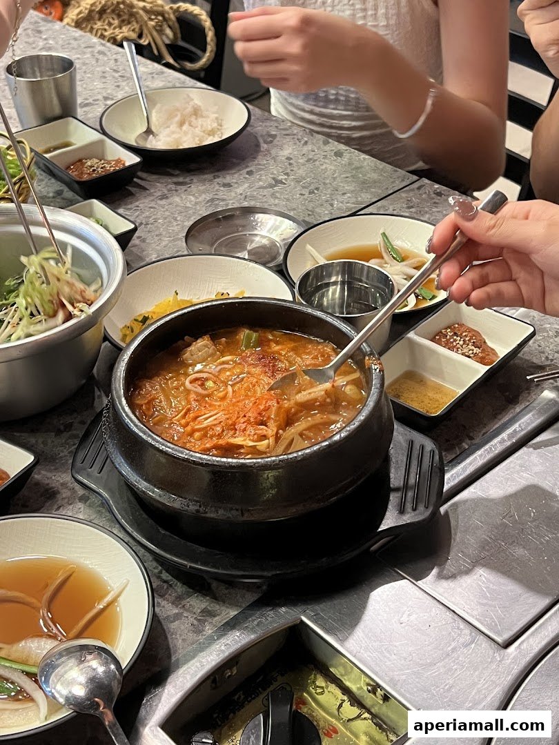 A table filled with Korean dishes, including a bubbling stew and various side dishes.