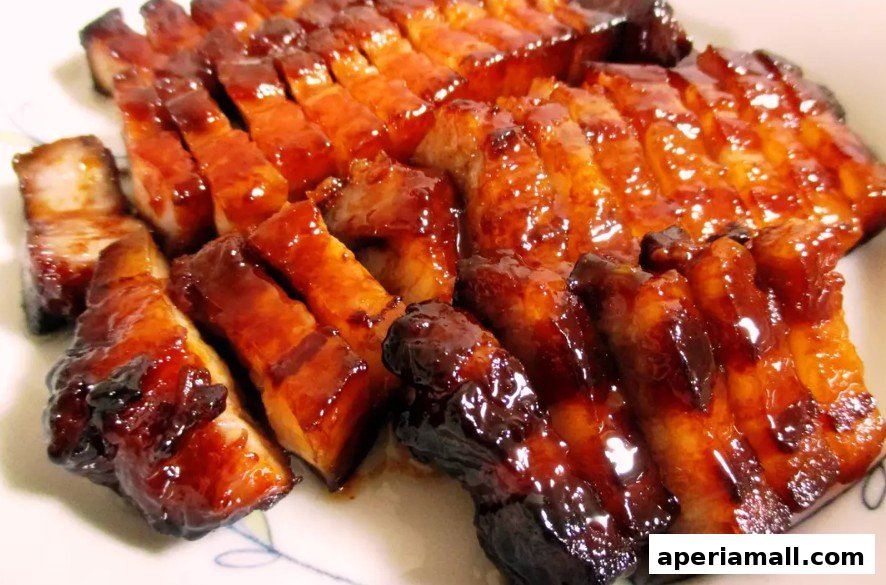 A close-up shot of glistening, sliced char siu pork on a white plate.