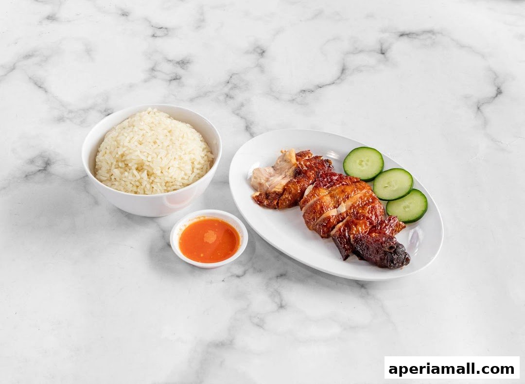 A plate of roasted chicken with rice and chili sauce, garnished with cucumber slices.