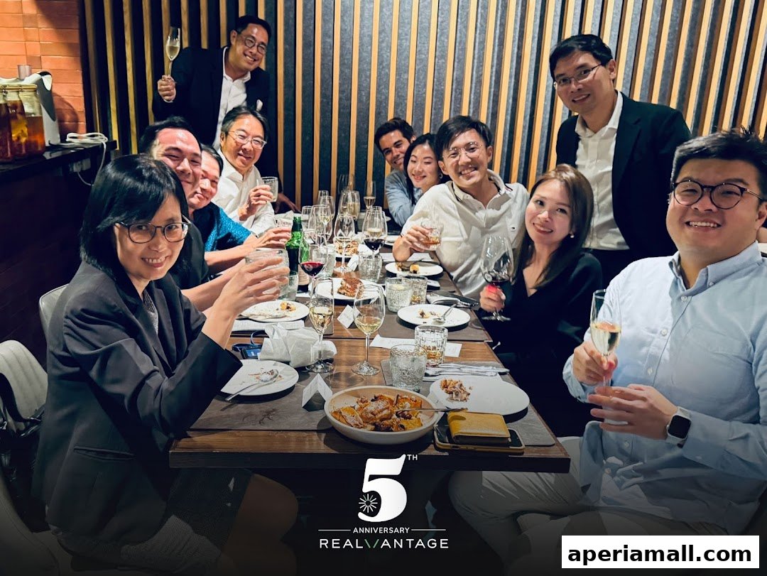 A group of people celebrating an anniversary at a dinner table with drinks and food.