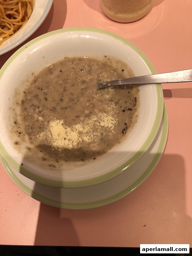 A bowl of creamy mushroom soup with grated cheese and a spoon.