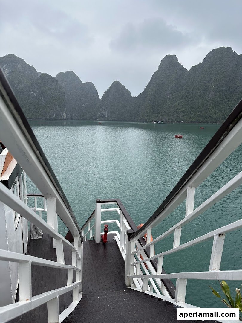 View of limestone karsts and calm turquoise water from a boat's staircase.
