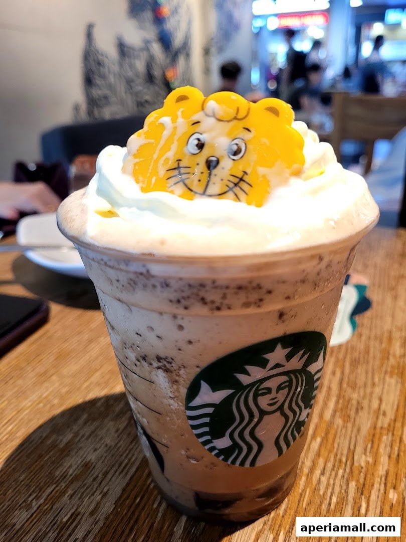 A Starbucks Frappuccino topped with whipped cream and a cute lion-shaped decoration.