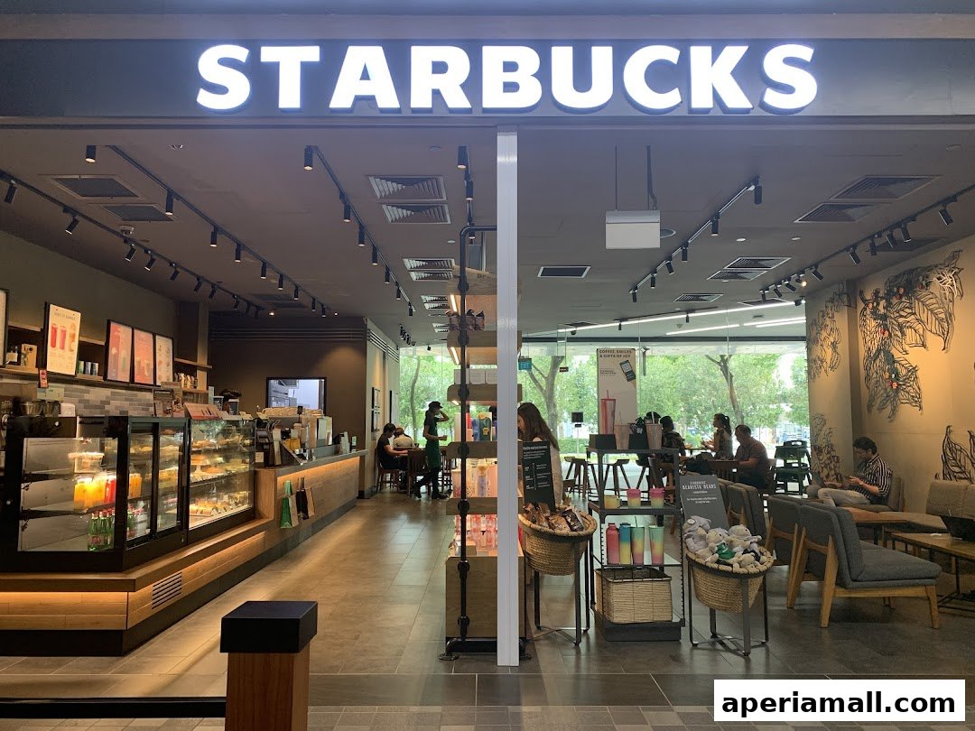 The exterior of a Starbucks coffee shop with customers inside and merchandise displayed.