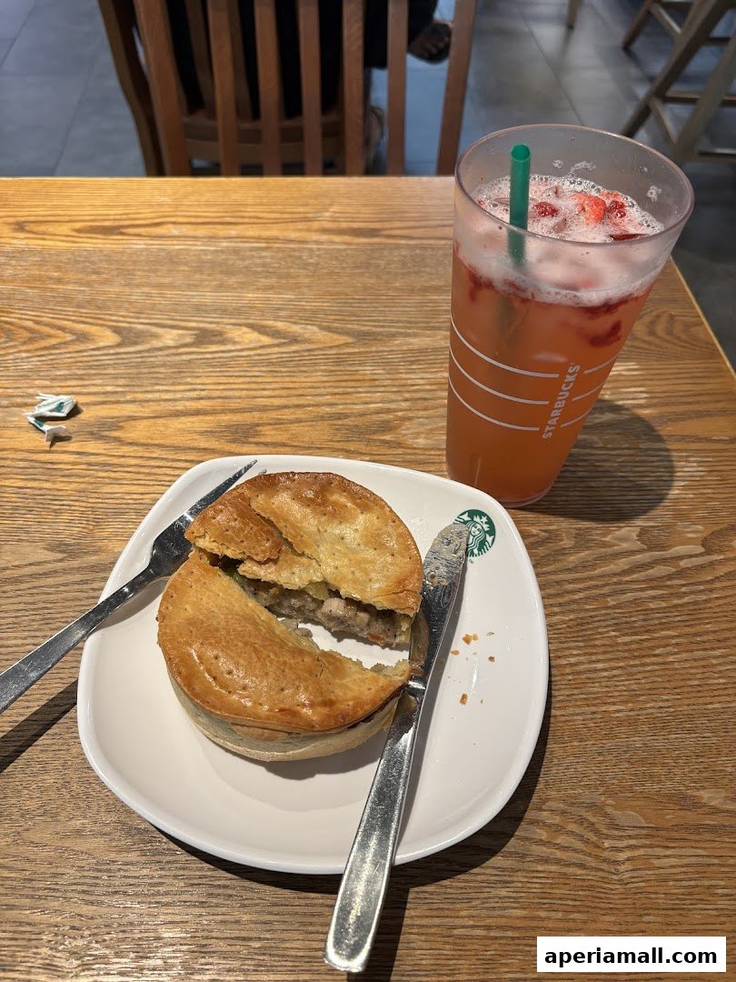 A savory pie and a refreshing strawberry drink on a wooden table at Starbucks.