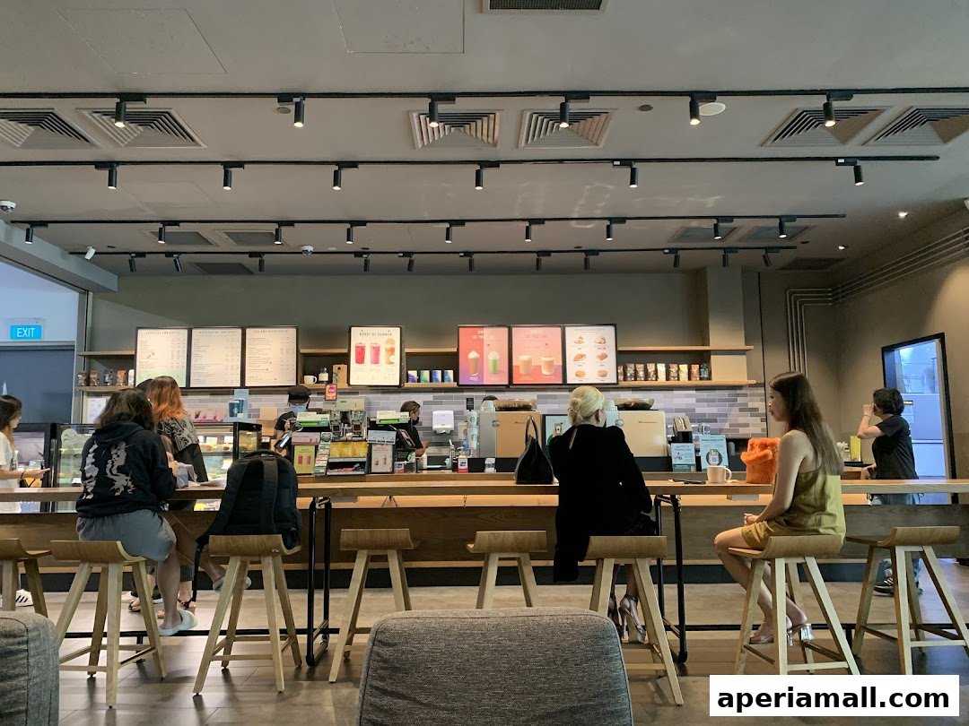 Customers are seated at a Starbucks counter, with baristas preparing drinks behind the counter.