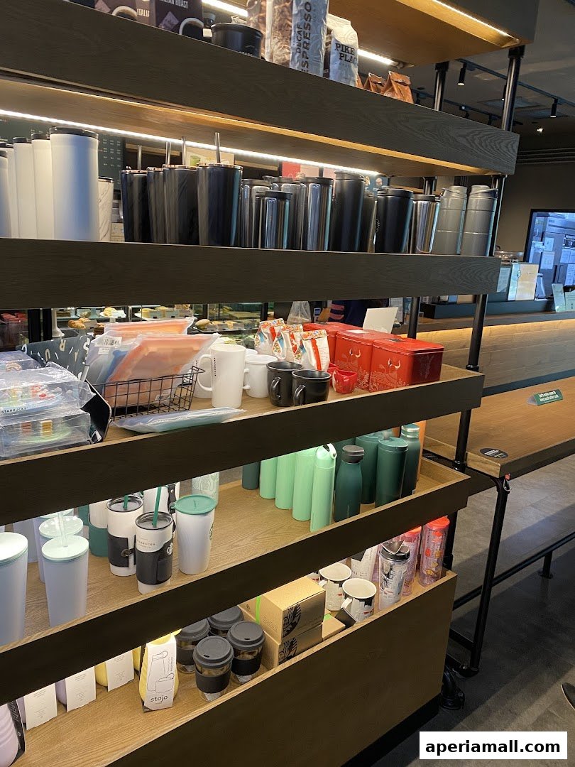 Shelves stocked with Starbucks merchandise including tumblers, mugs, and coffee bags.