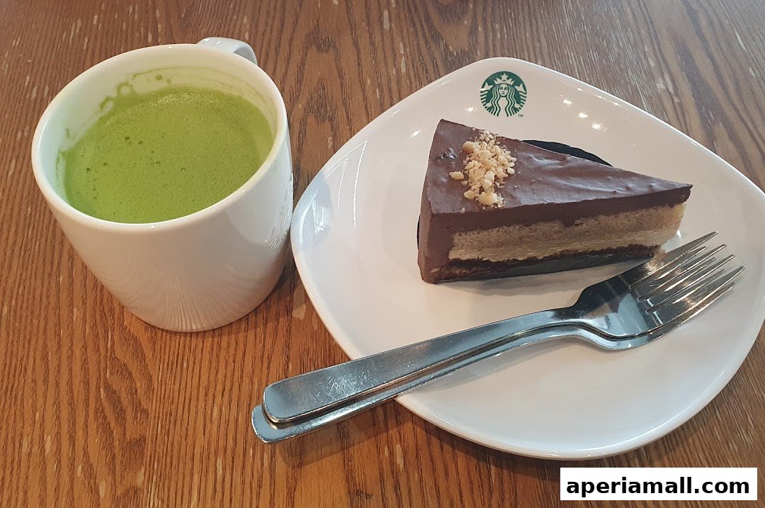 A slice of chocolate cake and a cup of green tea on a wooden table.