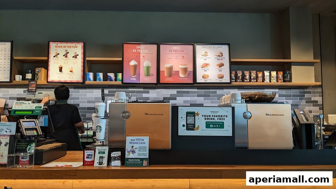 Starbucks counter with a barista preparing drinks and promotional posters on the wall.