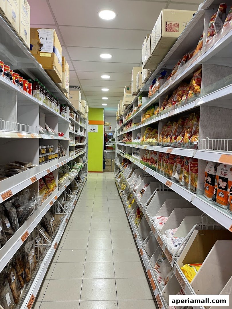 Aisle view of a supermarket with shelves stocked with various food products and dry goods.
