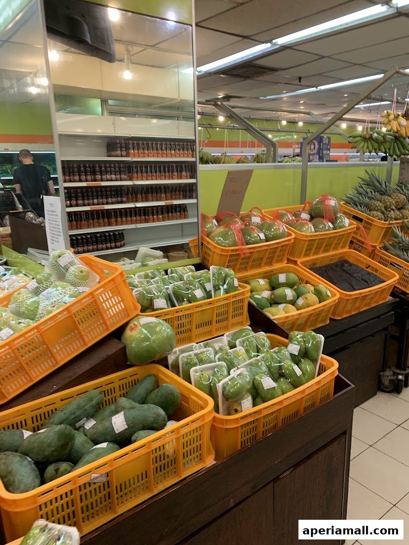 A display of fresh fruits like papayas, guavas, and pineapples in yellow baskets at a supermarket.