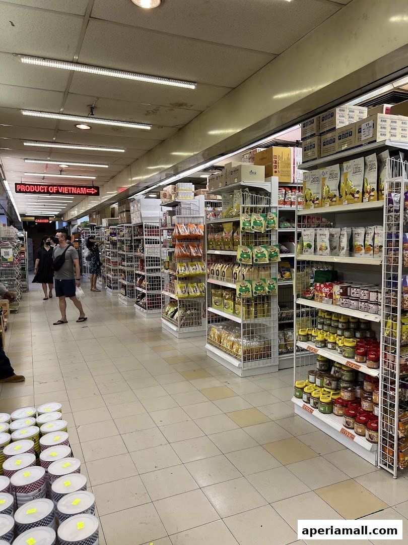 Aisle view of a supermarket with shelves stocked with various food products and customers browsing.