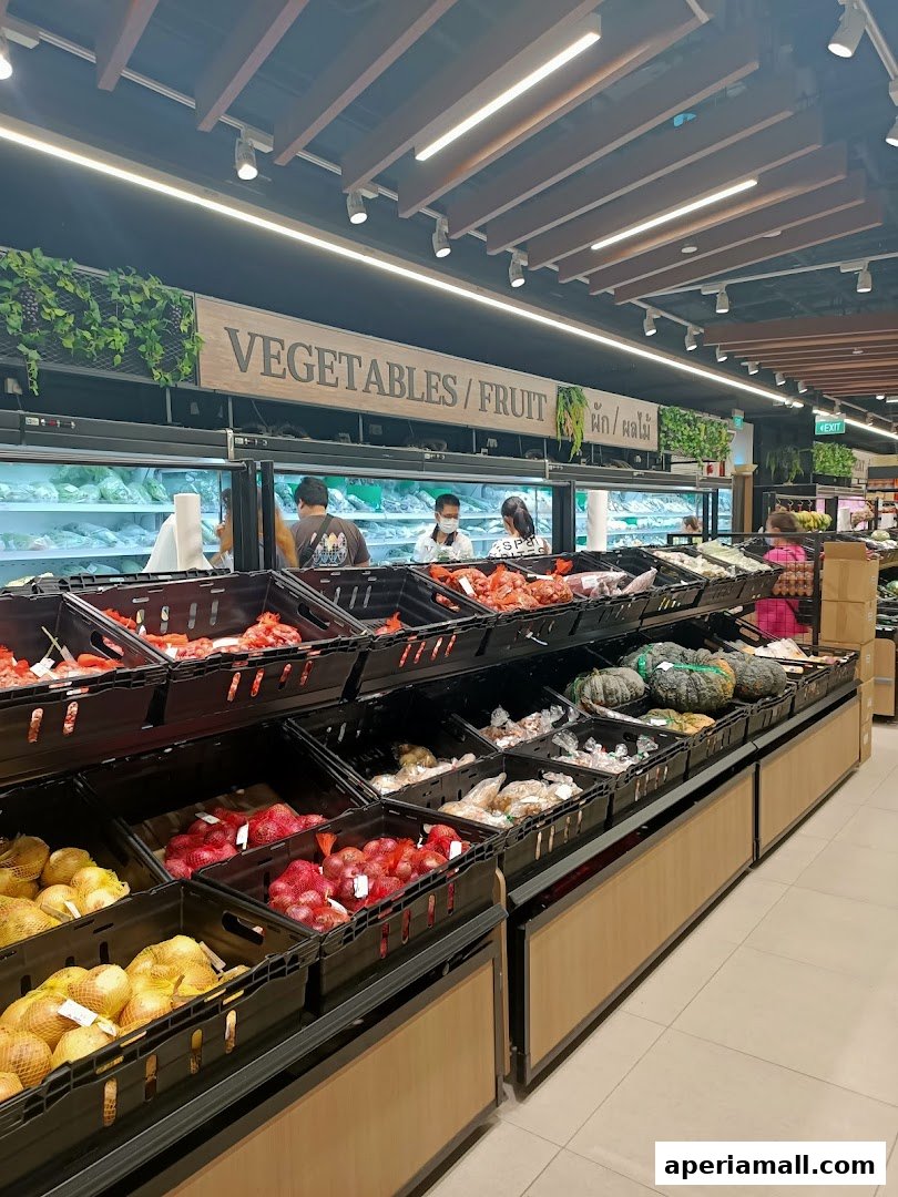A wide selection of fresh vegetables and fruits displayed in crates at a supermarket.