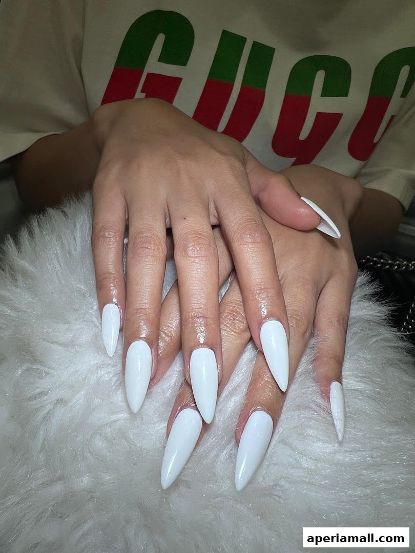 Close-up of hands with perfectly manicured white stiletto nails.