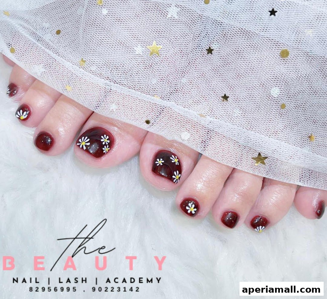 Close-up of feet with dark red toenails adorned with white daisy nail art.