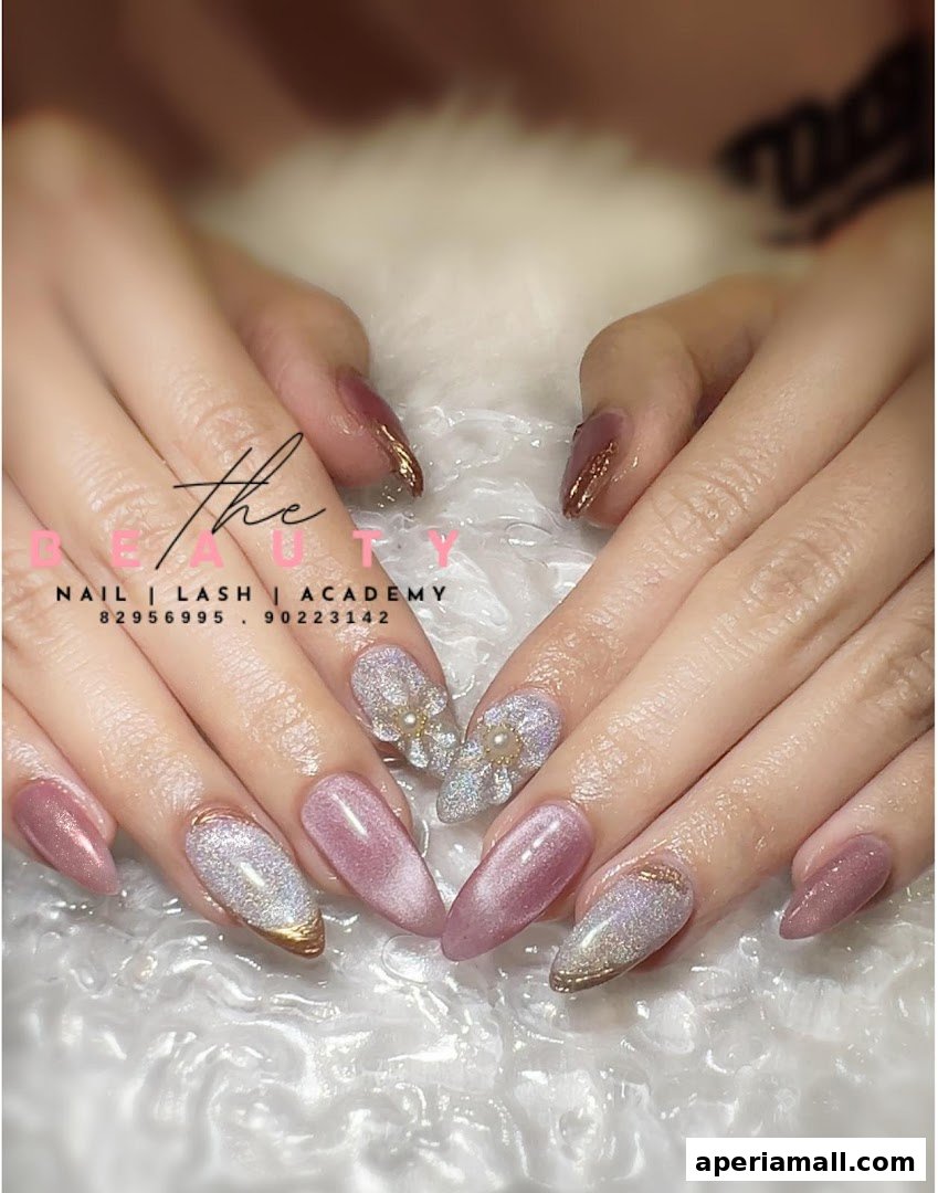 Close-up of hands with beautifully decorated nails featuring glitter and pearl accents.