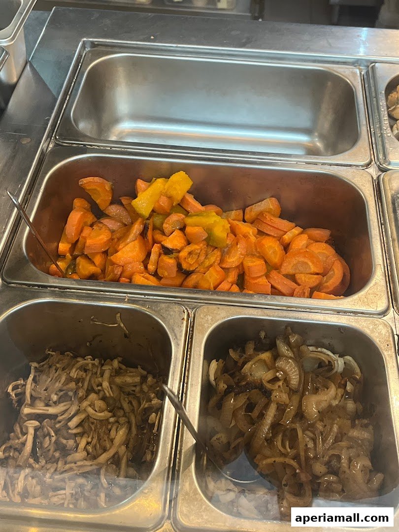 A close-up of three stainless steel food pans filled with cooked vegetables.